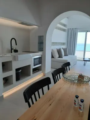 a kitchen and living room with a table and chairs at Sfakia Seaside luxury Suites in Khóra Sfakíon