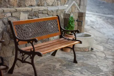 a wooden bench sitting next to a stone wall at STAMATOGIANNIS Traditional Apartments in Kalivianí