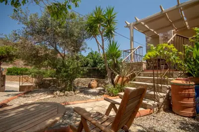 a patio with a wooden bench and stairs with trees at STAMATOGIANNIS Traditional Apartments in Kalivianí