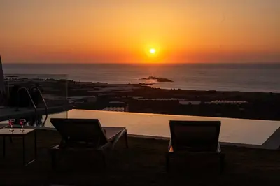 a sunset over the ocean with two chairs and a pool at Villa Maritini in Chania Town