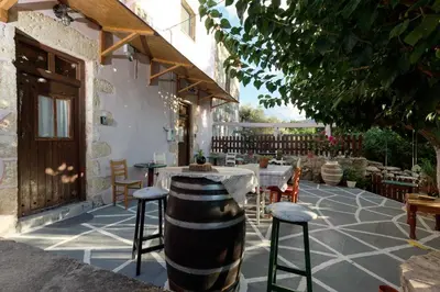 a patio with a table and chairs and a barrel at Vryses Crete-Village Vibes in Vryses