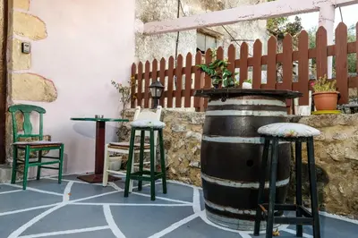 a patio with a barrel and two chairs and a table at Vryses Crete-Village Vibes in Vryses