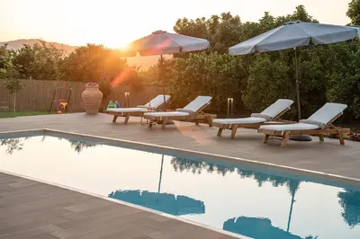 a swimming pool with chairs and umbrellas next to at Villa Enny, 3 BD with Private Heated Pool in Ayiá