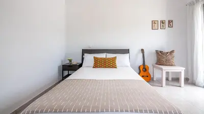 a white bedroom with a bed and a guitar at Lahardi - Seaside House in Kissamos