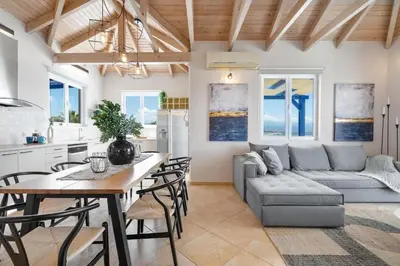 a kitchen and living room with a table and a couch at Villa Hemera ocean view private heated pool in Chorafakia