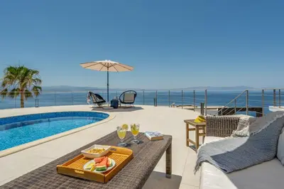 a villa with a swimming pool with a table and chairs at Villa Hemera ocean view private heated pool in Chorafakia