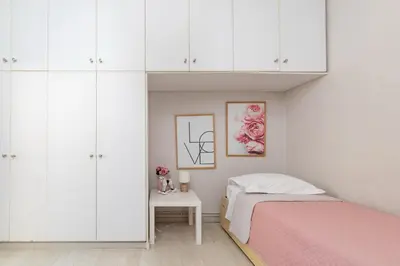 a bedroom with white cabinets and a bed and a table at Chania dream apartment in Chania Town