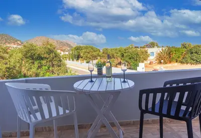 a table with two chairs and wine glasses on a balcony at Anastasia Home in Palaiochóra