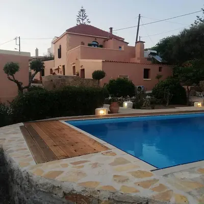 a swimming pool with a house in the background at Villa Terpsi in Ravdhoúkha