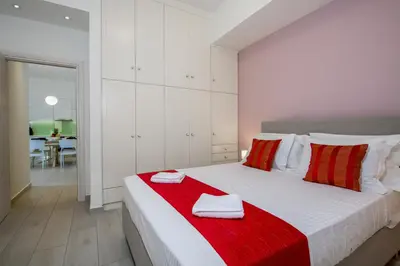 a white bedroom with a large white bed with red pillows at Belle Verte City Chania in Chania Town