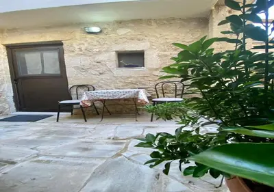 a patio with two chairs and a table and a door at Nikos Traditional House in Maláthiros