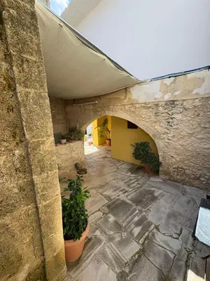 a stone building with an archway and potted plants at Nikos Traditional House in Maláthiros