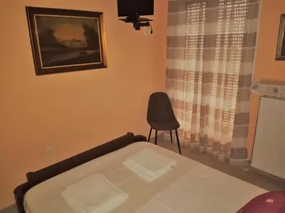 a bedroom with a bed and a chair next to a window at Alkioni City Apartments in Chania Town