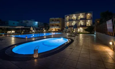 a swimming pool at night with buildings in the background at Giannarakis Beach in Stalos