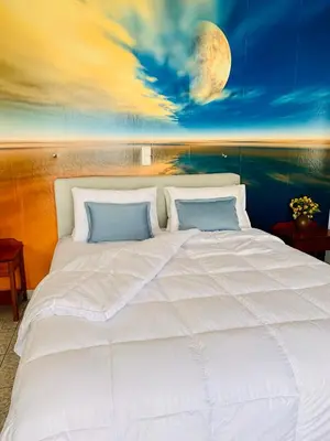 a large white bed with a painting on the wall at Ouranos Studios in Kalamaki Chanion