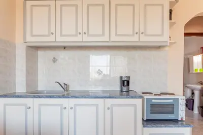 a kitchen with white cabinets and a sink and a microwave at CHRISTINE SEASIDE APARTMENTS IN CHANIA in Stalos