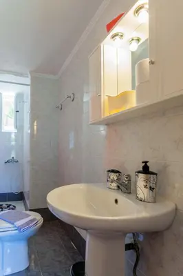 a bathroom with a white sink and a mirror at CHRISTINE SEASIDE APARTMENTS IN CHANIA in Stalos