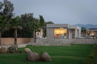 a house with a green lawn in front of it at Artemis Villa, Beachfront Retreat with Heated Pool, By ThinkVilla in Tavronitis