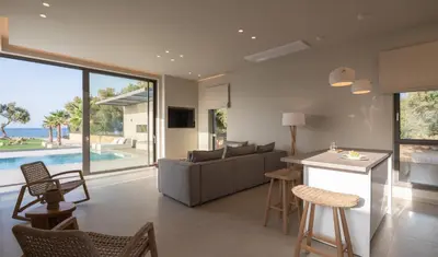 a kitchen and living room with a couch and a table at Artemis Villa, Beachfront Retreat with Heated Pool, By ThinkVilla in Tavronitis