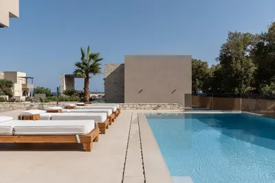 a swimming pool with chaise lounges next to a building at Amalthia Villa, Heated Pool & Walk to the Beach, By ThinkVilla in Tavronitis