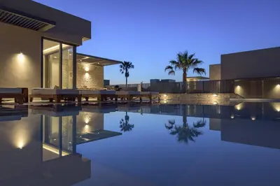 a villa with a swimming pool at night at Amalthia Villa, Heated Pool & Walk to the Beach, By ThinkVilla in Tavronitis