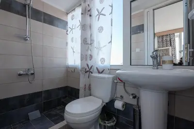 a bathroom with a white toilet and a sink at Calliope Rooms in Kissamos