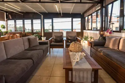 a living room with couches and tables and windows at Calliope Rooms in Kissamos