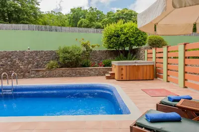 a swimming pool in a yard with a fence and an umbrella at Arhontika Villas in Élos