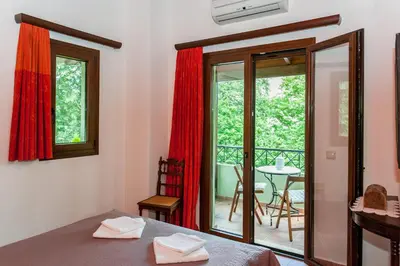 a room with a bed and a balcony with a table at Arhontika Villas in Élos