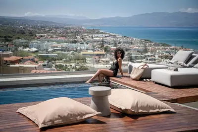 a woman sitting on the edge of a swimming pool at Alectrona Living Crete, Apartment RocSea in Plataniás