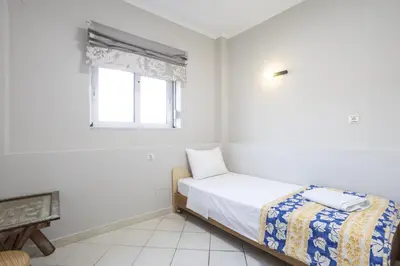 a white bedroom with a bed and a window at Sofia's seaview house in Plataniás