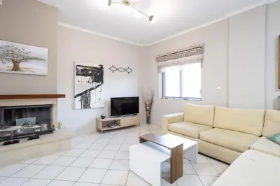 a white living room with a couch and a tv at Sofia's seaview house in Plataniás
