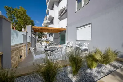 a patio with white chairs and tables on a building at Deluxe City Hotel in Chania Town