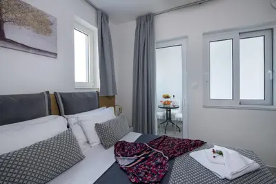 a bedroom with a bed and two windows at Deluxe City Hotel in Chania Town