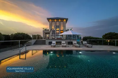 a pool with chairs and a gazebo at sunset at Seacrete villas in Chania Town