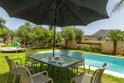 a table and chairs with an umbrella next to a pool at Villa Eftychia - villa with 2 private pools!!! by PosarelliVillas in Almirida
