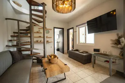 a living room with a spiral staircase and a couch at Villa Eftychia - villa with 2 private pools!!! by PosarelliVillas in Almirida