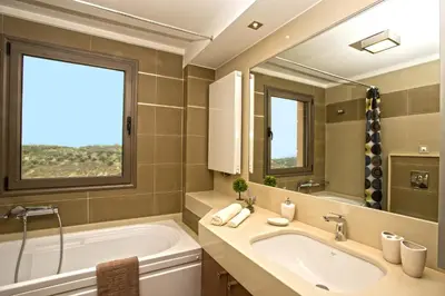a bathroom with a tub and a sink and a mirror at Margarita's Villas in Chania Town