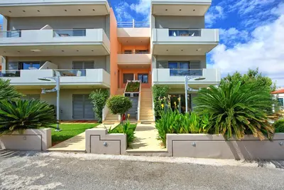 an apartment building with palm trees in front of it at Cabanavillas MILANO by PosarelliVillas in Agia Marina Nea Kydonias
