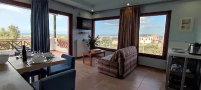 a living room with a table and chairs and large windows at Villa Koulouridi Agritourism in Daratso