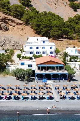 a group of chairs and umbrellas on a beach at Hotel Agia Roumeli by the SEA in Agia Roumeli