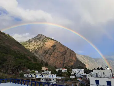a rainbow over a city with a mountain at Hotel Agia Roumeli by the SEA in Agia Roumeli