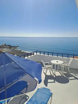 a patio with a table and chairs and the ocean at Hotel Agia Roumeli by the SEA in Agia Roumeli