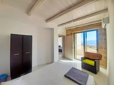a bedroom with a bed and a chair and a window at Bangalows Stylianos in Kounoupítsa