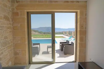 a house with a glass door leading to a patio at Bangalows Stylianos in Kounoupítsa