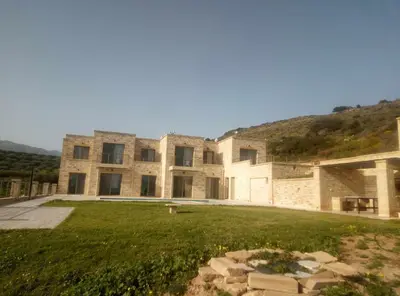 a large stone building with a grass field in front of it at Vilitsa Stylianos in Kounoupítsa