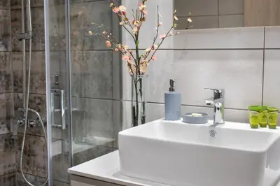 a bathroom with a white sink and a vase with flowers at Casa Gardenia-modern apartment next to the beach, near Old Town in Chania Town