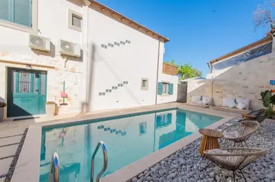 a swimming pool with two chairs next to a house at Villa Kirke in Próvarma