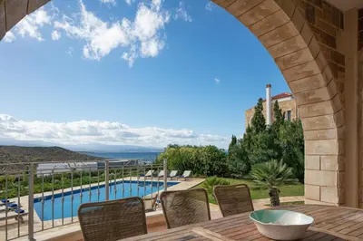a view of a swimming pool from a patio with chairs at Lake and Sea Villa in Tersanas