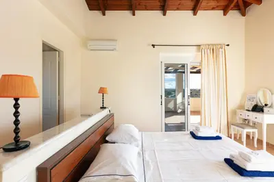 a bedroom with a bed and a lamp and a balcony at Lake and Sea Villa in Tersanas